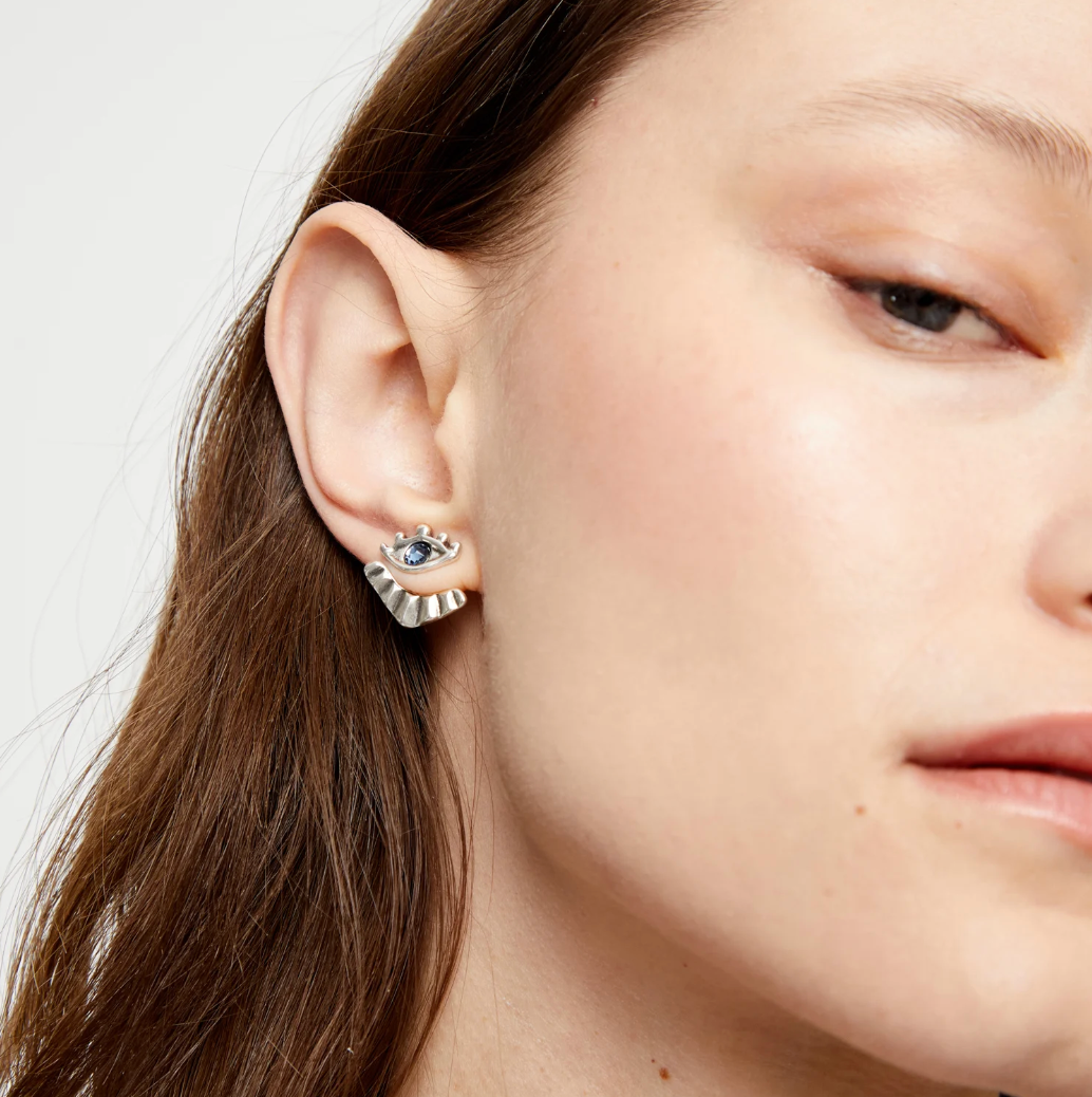 Pendientes bañados en plata en forma de ojo con pestañas y cristal facetado azul
