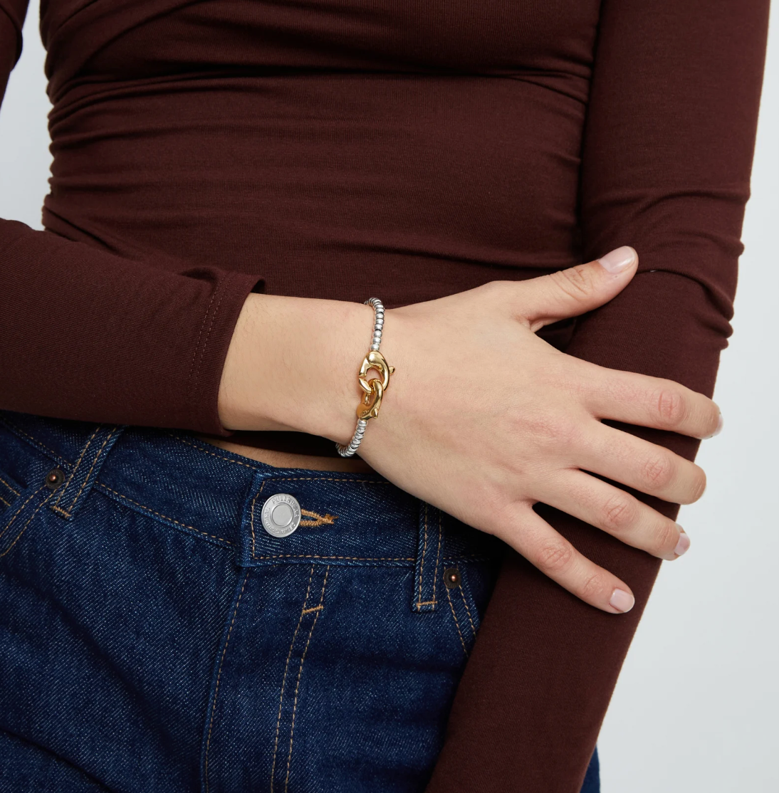 Pulsera de bolas pequeñas bañada en oro con mosqueton entrelazado en oro