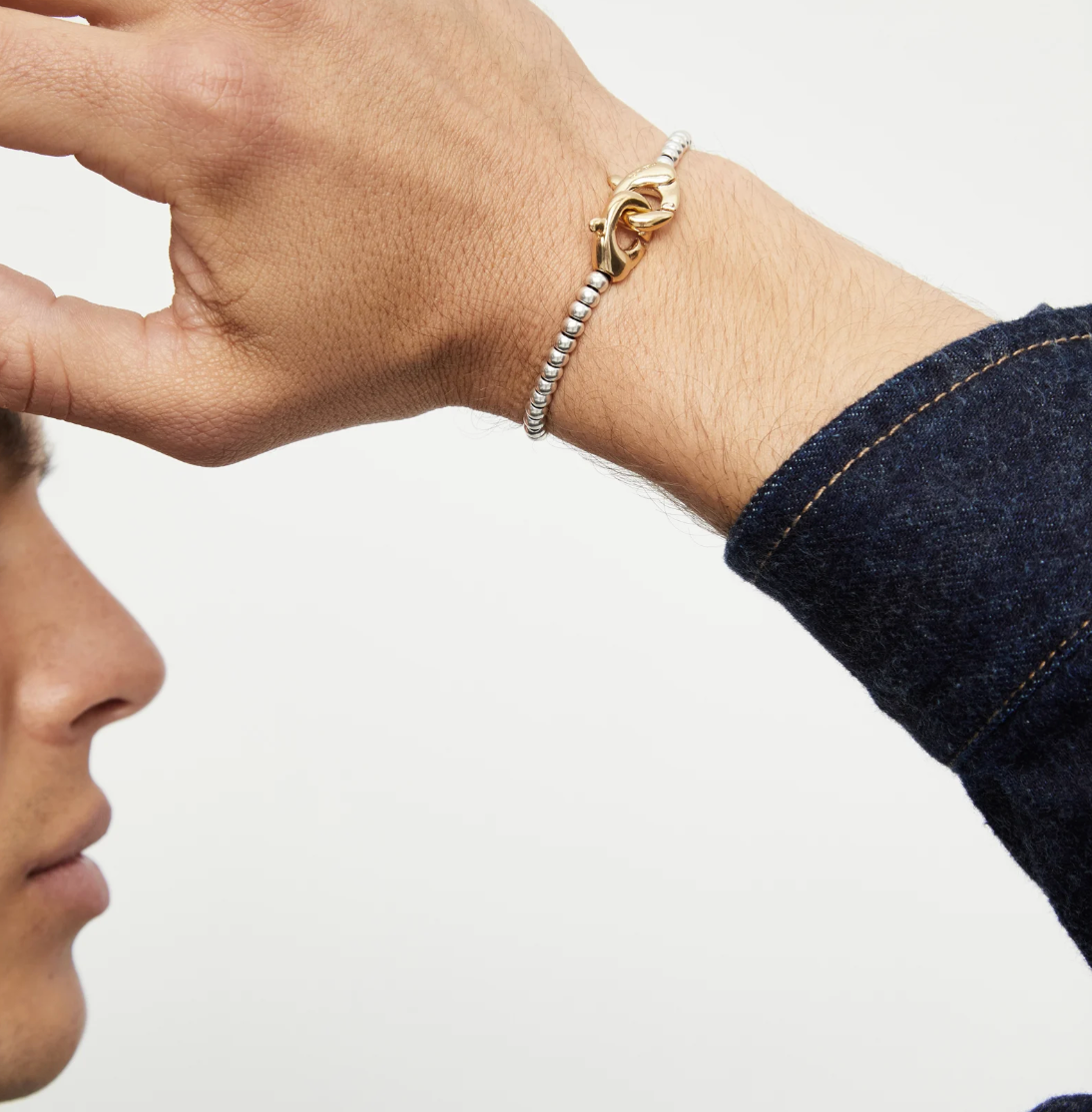 Pulsera de bolas pequeñas bañada en oro con mosqueton entrelazado en oro